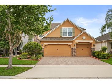 Charming two-story home with a brick driveway, two-car garage, and manicured landscaping at 1613 Water Elm Ct, Orlando, FL 32825