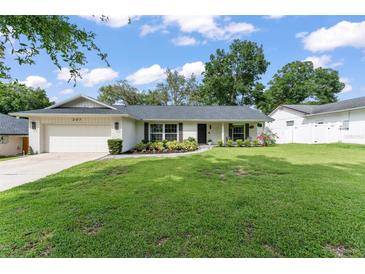 Charming single-story home featuring a lush front lawn, brick accents, and a well-manicured garden at 207 Ramsbury Ct, Longwood, FL 32779