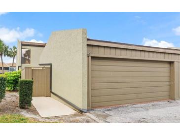 Attached one-car garage with a neutral colored door and a walkway to a private entrance at 2500 21St Nw St # 58, Winter Haven, FL 33881