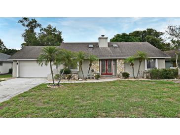 Charming single-story home features stone accents, a well-manicured lawn, and mature landscaping with palm trees at 353 Wekiva Cove Rd, Longwood, FL 32779