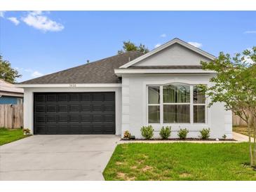 Charming single-story home with a well-manicured lawn, black garage door, and neutral paint at 3622 Huntwicke Blvd, Davenport, FL 33837