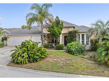Inviting single-story home featuring a well-manicured lawn and lush tropical landscaping at 407 Grand Reserve Dr, Davenport, FL 33837