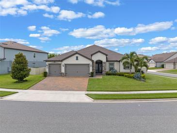 Beautiful single-story home with manicured lawn, brick driveway, and a three-car garage at 418 Gleaming Andover Way, Longwood, FL 32779