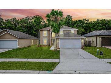 Two-story home features a well-manicured lawn, a two-car garage, and mature palm trees against a vibrant sunset backdrop at 4519 Willamette Cir, Orlando, FL 32826