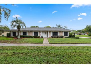 Charming single-story home featuring a well-manicured lawn and a mature palm tree in the front yard at 5089 Jennifer Pl, Orlando, FL 32807