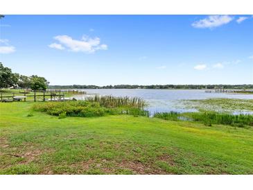 Expansive backyard with lush green lawn and waterfront access to a scenic lake at 942 Beach Breeze Dr, Orlando, FL 32835