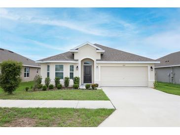 Charming single-story home featuring a two-car garage, well-maintained lawn, and inviting front entrance at 1061 Citrus Landings Blvd, Davenport, FL 33837