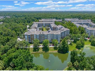 Scenic aerial view of multi-Gathering buildings surrounded by lush greenery and a tranquil pond at 1200 Ironsmith Dr # 508, Celebration, FL 34747
