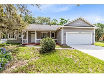 Charming gray home with a two car garage, covered porch, and well maintained front yard at 13018 S Sunset Ter, Winter Garden, FL 34787
