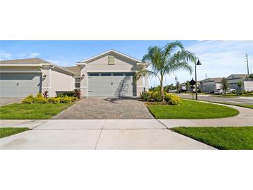 Charming single-story home featuring a paved driveway, manicured lawn, and lush landscaping with palm tree at 1650 Key Bay Trl, Kissimmee, FL 34747