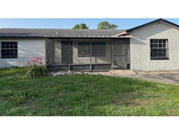 A cozy backyard showing the screened-in porch, grass, and landscaping around this cozy home at 2085 San Jose Blvd, Orlando, FL 32808
