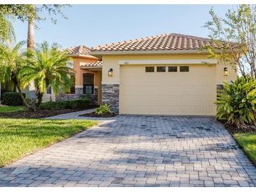 Charming home featuring a tile roof, stone accents, a two-car garage, and a well-manicured lawn at 223 Monterey St, Kissimmee, FL 34759
