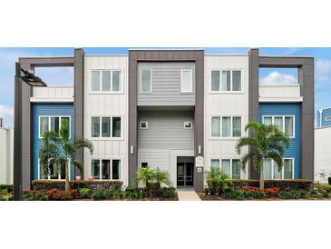 Modern three-story building with gray, white and blue color scheme and decorative palm trees in front at 7740 Sandy Ridge Dr # 114, Reunion, FL 34747
