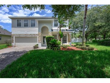 Charming two-story home with stone accents, manicured lawn and lush landscaping at 809 Kazaros Cir, Ocoee, FL 34761
