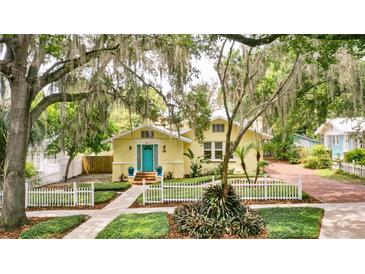 Charming yellow home with a lush front yard, white picket fence, and a bright blue front door at 835 Antonette Ave, Winter Park, FL 32789