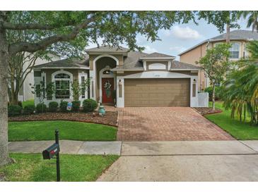 Charming single-Gathering home featuring a brick driveway, a well-maintained lawn, and a two-car garage at 15038 Masthead Landing Cir, Winter Garden, FL 34787