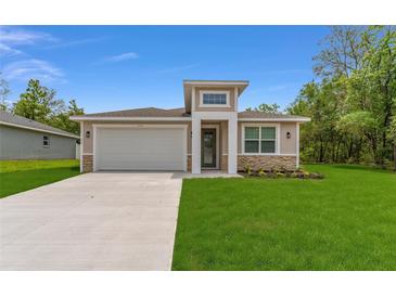 Charming single-story home featuring a well-manicured lawn, a two-car garage, and stone accents at 16357 Se 88Th Ct, Summerfield, FL 34491