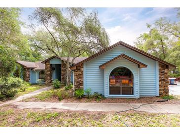 Charming single-story home featuring light blue siding, stone accents, arched window, and mature trees at 4933 Round Lake Rd, Apopka, FL 32712