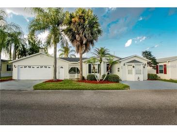 Charming single-story home with a well-manicured lawn, mature palm trees, and an attached two-car garage at 50989 Highway 27 # 176177, Davenport, FL 33897