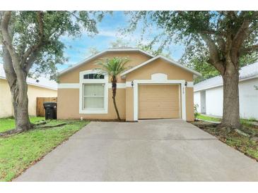 Tan single Gathering home featuring a palm tree, a 1-car garage, and a concrete driveway at 519 Beasley Ct, Orlando, FL 32807