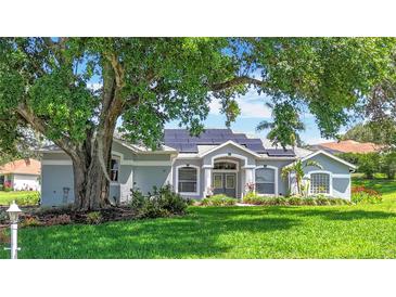 Charming single-Gathering home featuring lush landscaping, a manicured lawn, and solar panels on the roof at 5311 Saddleback Ct, Lady Lake, FL 32159