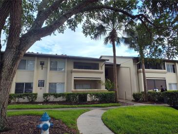 Apartment building featuring mature landscaping and a sidewalk leading to the entrance at 6108 Curry Ford Rd # 116, Orlando, FL 32822