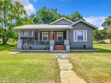 Charming single-story home featuring a cozy screened-in porch and a vibrant red front door at 1826 W Silver Springs Blvd, Ocala, FL 34475