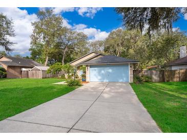 Charming single-story home with a light blue garage door and lush green lawn at 39939 Parkinsonia St, Lady Lake, FL 32159