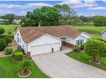Charming home with a two-car garage, brick-lined driveway, lush landscaping, and a manicured lawn at 4830 Summerbridge Cir, Leesburg, FL 34748