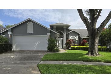 Charming gray two-story home with landscaped yard, mature tree, and a two car garage at 651 Oak Hollow Way, Altamonte Springs, FL 32714