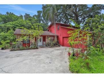 Charming red home with stone accents, lush landscaping, and a welcoming front entrance at 874 Quarters Ct, Port Orange, FL 32129