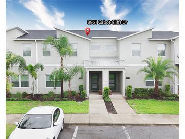 Contemporary townhome featuring clean lines, well-maintained landscaping, and a convenient parking space at 8961 Cabot Cliffs Dr, Davenport, FL 33896