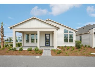 Charming single-story home featuring a covered front porch and stylish blue front door, surrounded by fresh landscaping at 2926 Sailhouse Drive, St Cloud, FL 34771