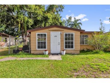 Tan home featuring a bright white door and matching window trim, complemented by potted flowers at 4133 Cepeda St, Orlando, FL 32811