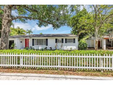Charming single-story home with a bright red door, white picket fence, and lush landscaping at 441 S Primrose Dr, Orlando, FL 32803