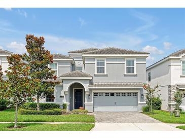 Charming two-story home with a gray exterior, well-manicured lawn, and a brick-paved driveway at 1521 Flange Dr, Davenport, FL 33896