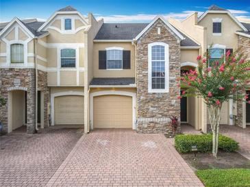 Attractive townhome with brick driveway, manicured lawn, and stone facade, creating inviting curb appeal at 15822 Woodland Spring Ct, Orlando, FL 32828