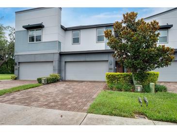 Modern townhome featuring a brick driveway, two-car garage, manicured landscaping, and a stylish architectural design at 1624 Little Wren Ln, Winter Park, FL 32792