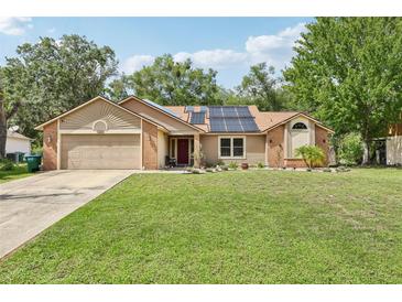 Charming single-story home featuring a well-manicured lawn, solar panels, and a two-car garage at 2180 Captain Dr, Deltona, FL 32738