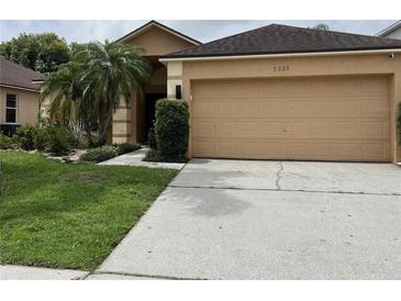 Charming single-story home with a well-maintained lawn, palm tree, and a beige two-car garage at 3224 Holland Dr, Orlando, FL 32825