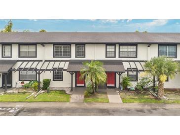 Charming townhome with a red door, a well-kept lawn and beautiful palm trees at 5662 Royal Pine Blvd # 24, Orlando, FL 32807