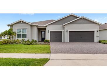 Well-maintained home exterior featuring a two-car garage, paver driveway, and manicured landscaping at 6348 Mossy Oak Rd, St Cloud, FL 34771