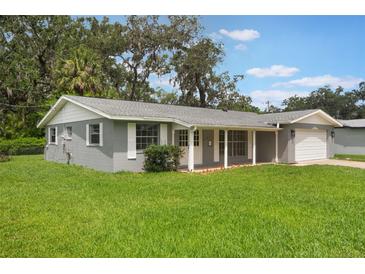 Charming single-story home with a gray exterior, white trim, and a spacious front yard with mature trees at 2050 Anne Cir, South Daytona, FL 32119