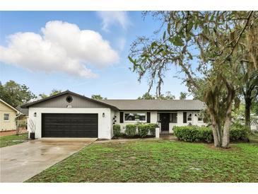 Charming white brick home featuring a black garage door and beautifully landscaped front yard at 7307 Grace Rd, Orlando, FL 32819