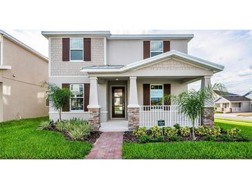 Charming two-story home featuring a welcoming front porch and professionally landscaped front yard at 9106 Cut Shot Dr, Winter Garden, FL 34787