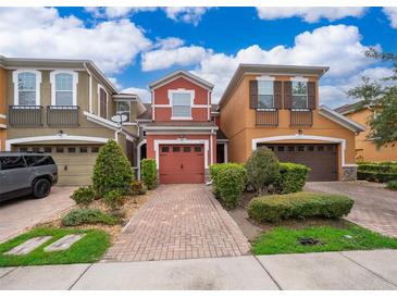Charming townhomes with brick driveways, well-kept lawns, and attached garages under a bright blue, partly cloudy sky at 9539 Silver Buttonwood St, Orlando, FL 32832