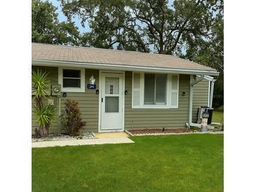 Charming single-story home featuring light green siding, a well-manicured lawn, and a welcoming front entrance at 10301 Us Highway 27 # 34, Clermont, FL 34711