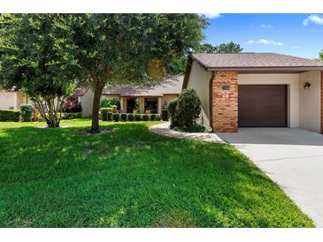 Charming single-story home featuring a well-manicured lawn, mature trees, and a brick-accented garage at 154 Golf Club Dr # 154, Longwood, FL 32779