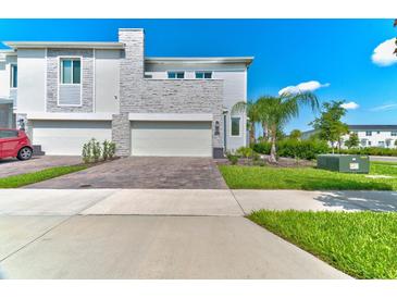Modern townhome with a two-car garage, stone accents, and well-maintained landscaping, perfect for stylish living at 224 Nine Iron Dr, Davenport, FL 33896