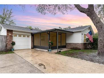 Charming home featuring a screened front porch, brick accents, attached garage, and a well-maintained front yard at 407 Ventura Dr, Sanford, FL 32773
